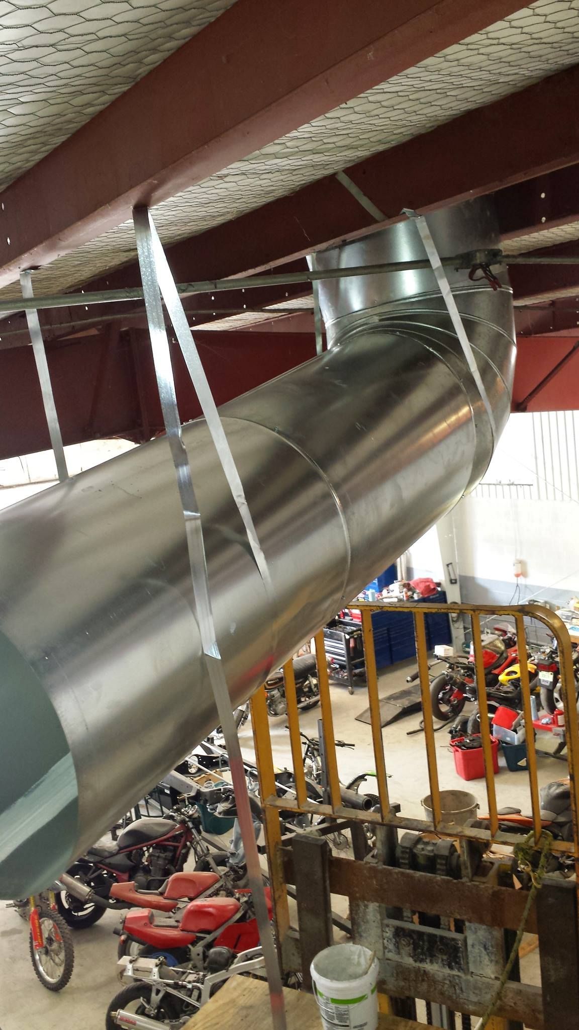 A bunch of motorcycles are parked in a garage under a ceiling.