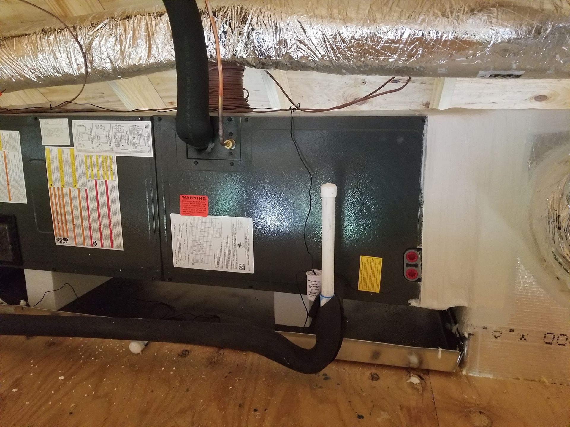 A black box with a hose attached to it is sitting on top of a wooden floor.