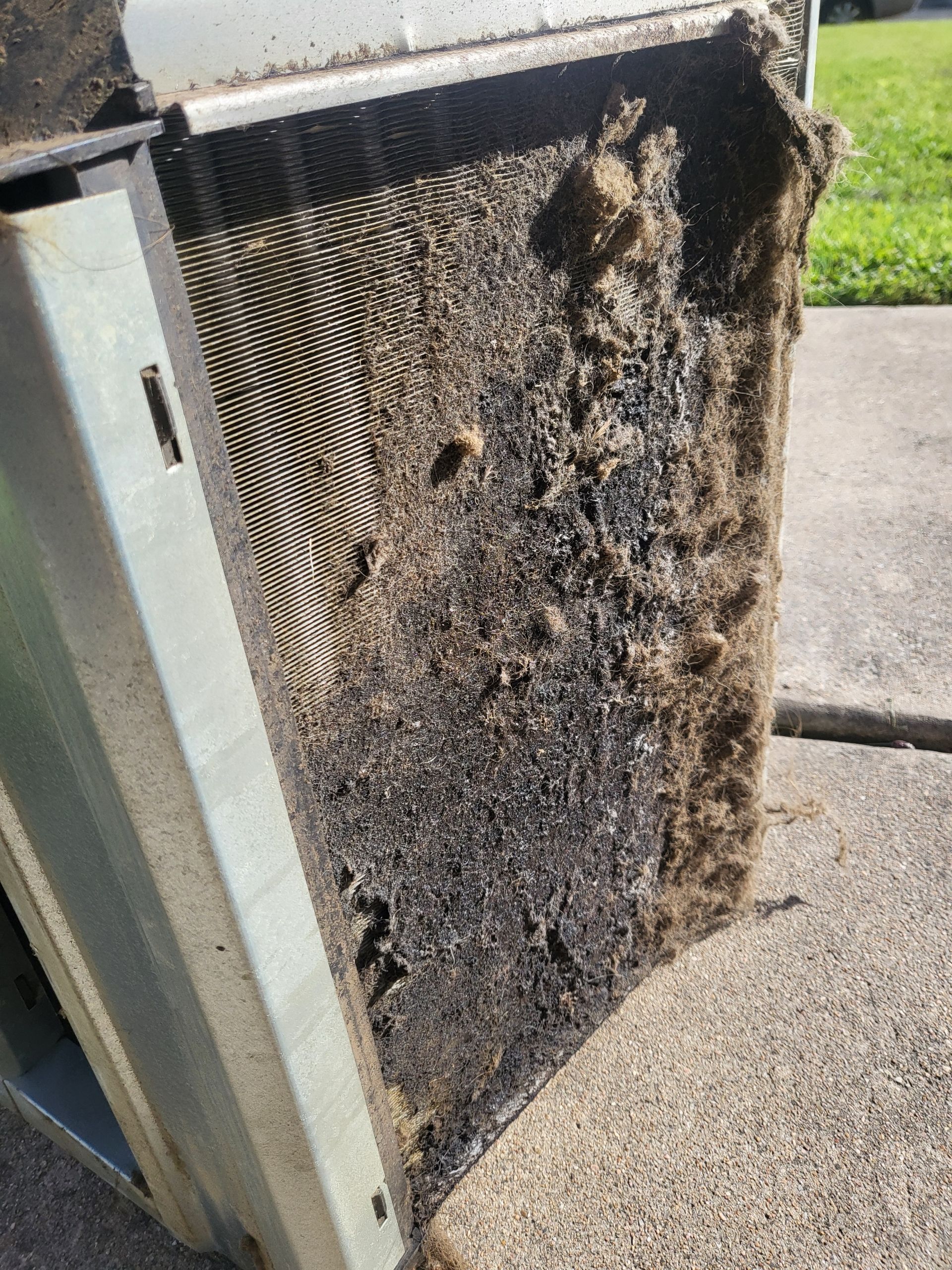 A close-up of a dirty air filter on a sidewalk