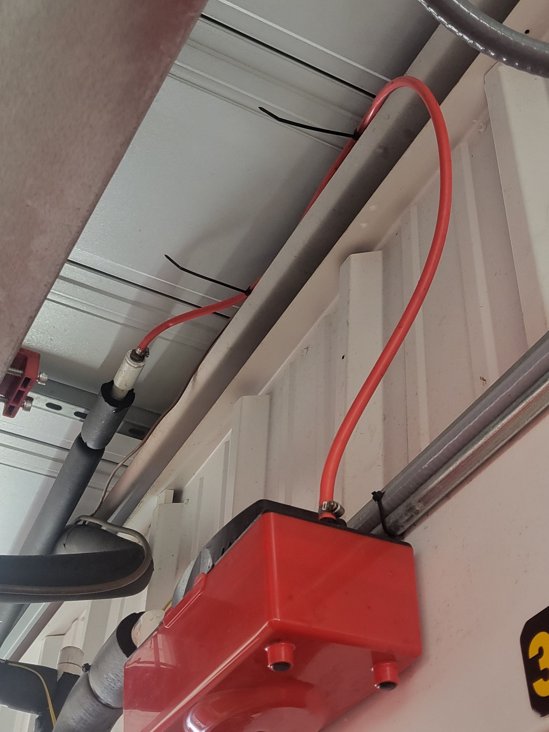 A red box with a hose attached to it and the number 3 on the wall