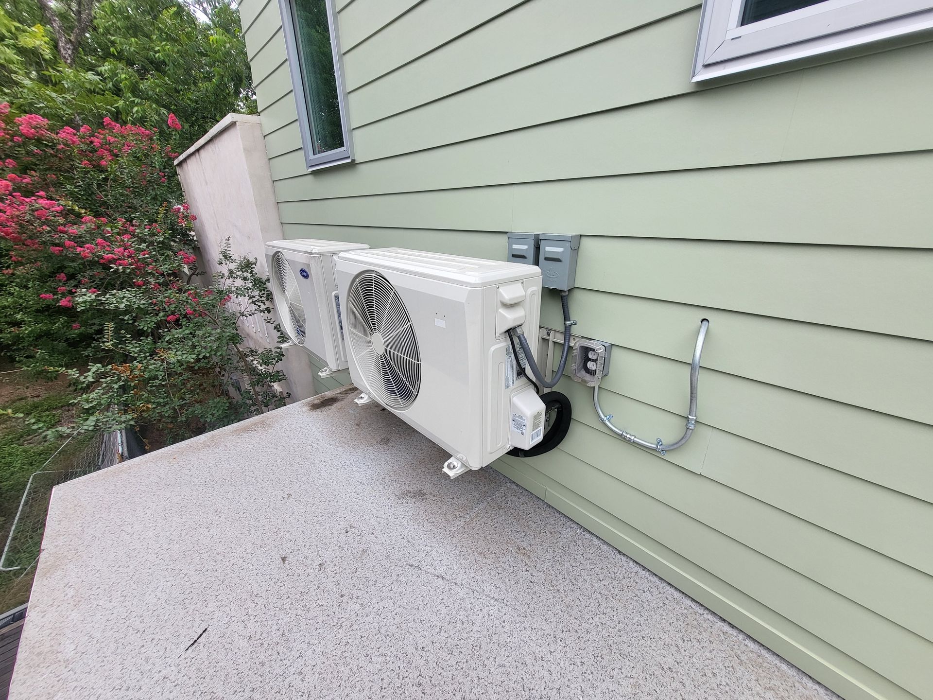 A couple of air conditioners mounted on the side of a house