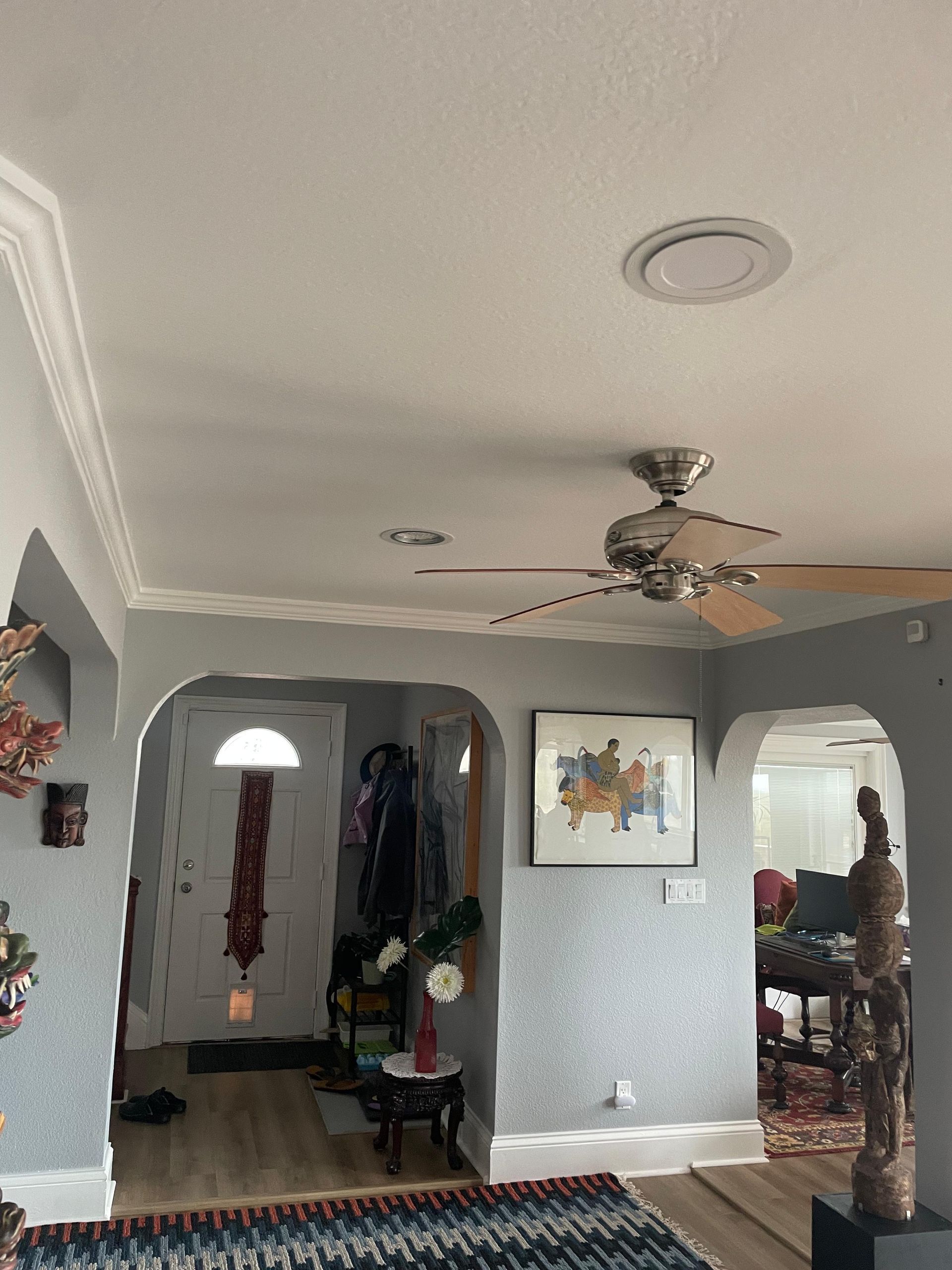 AFTER: Living room with ceiling fan, arched openings, wall art, and a view into another room