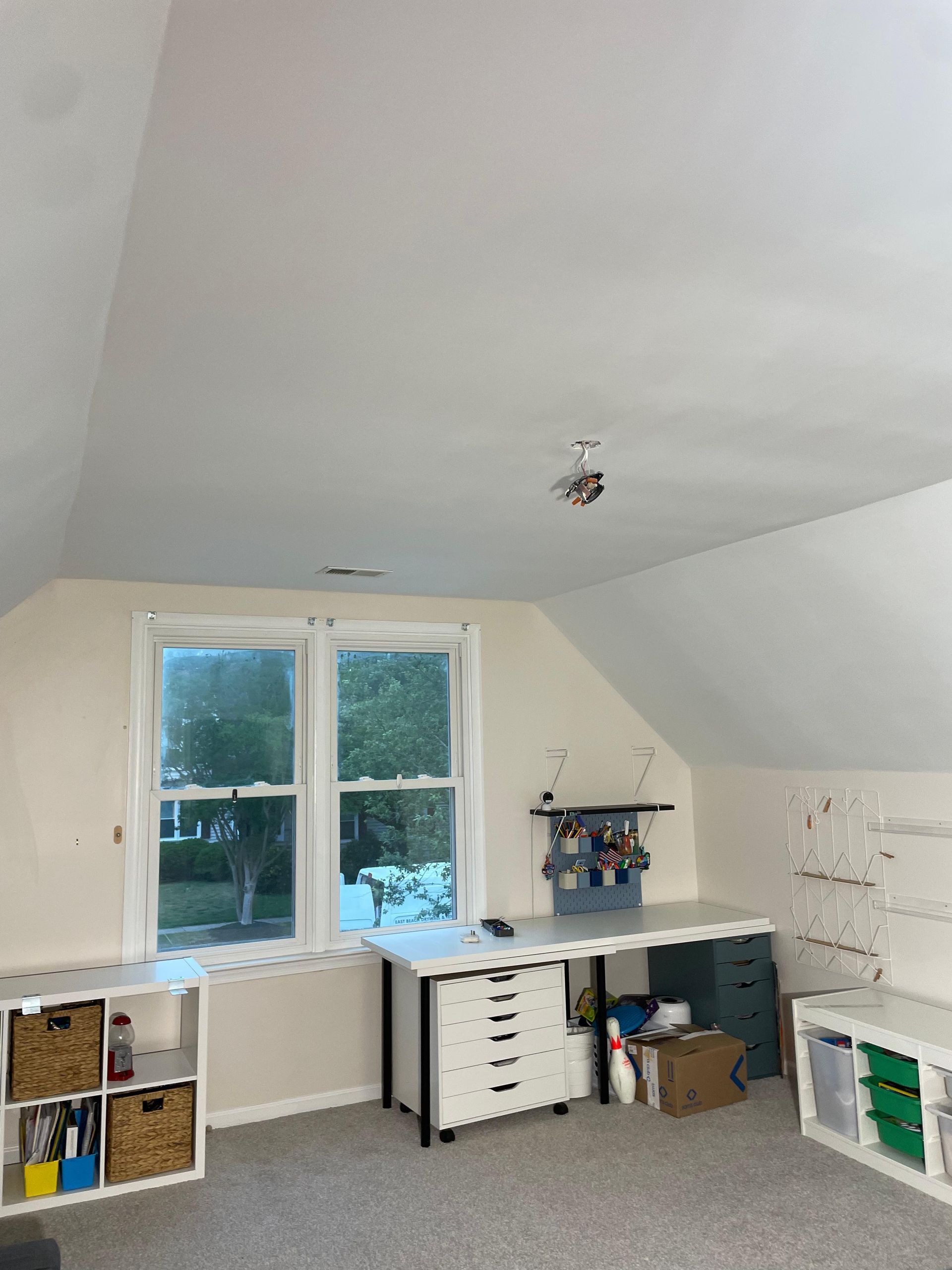 AFTER: Bright attic room with sloped ceiling, window, toy shelves, and a play/work desk area