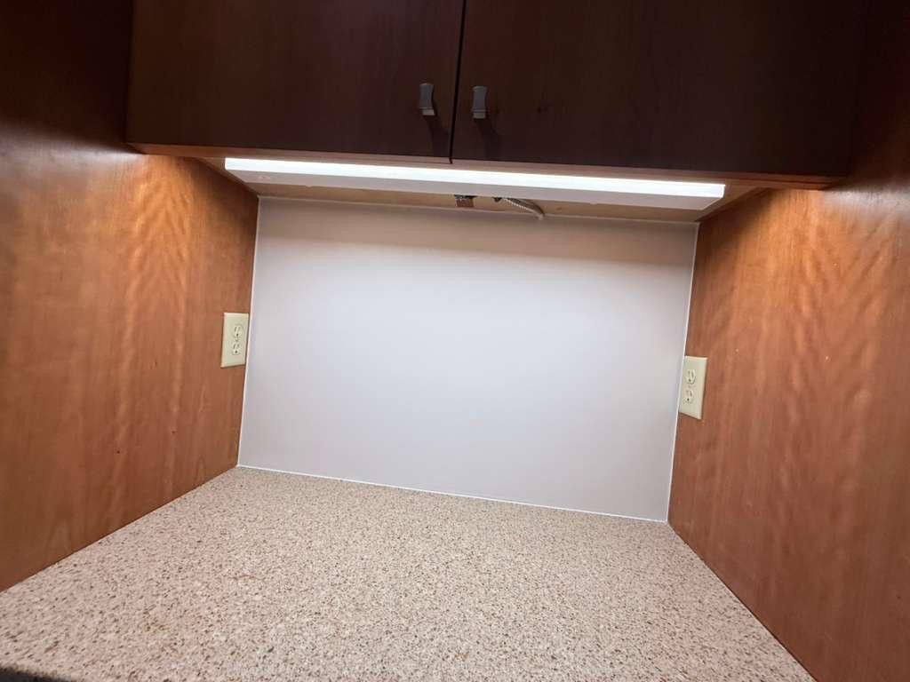 Empty unfinished room with drywall, two windows, and construction tools on a concrete floor.