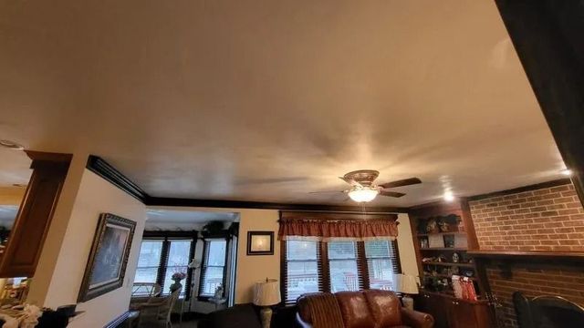 Living room with leather sofas, brick fireplace, ceiling fan, and framed wall art