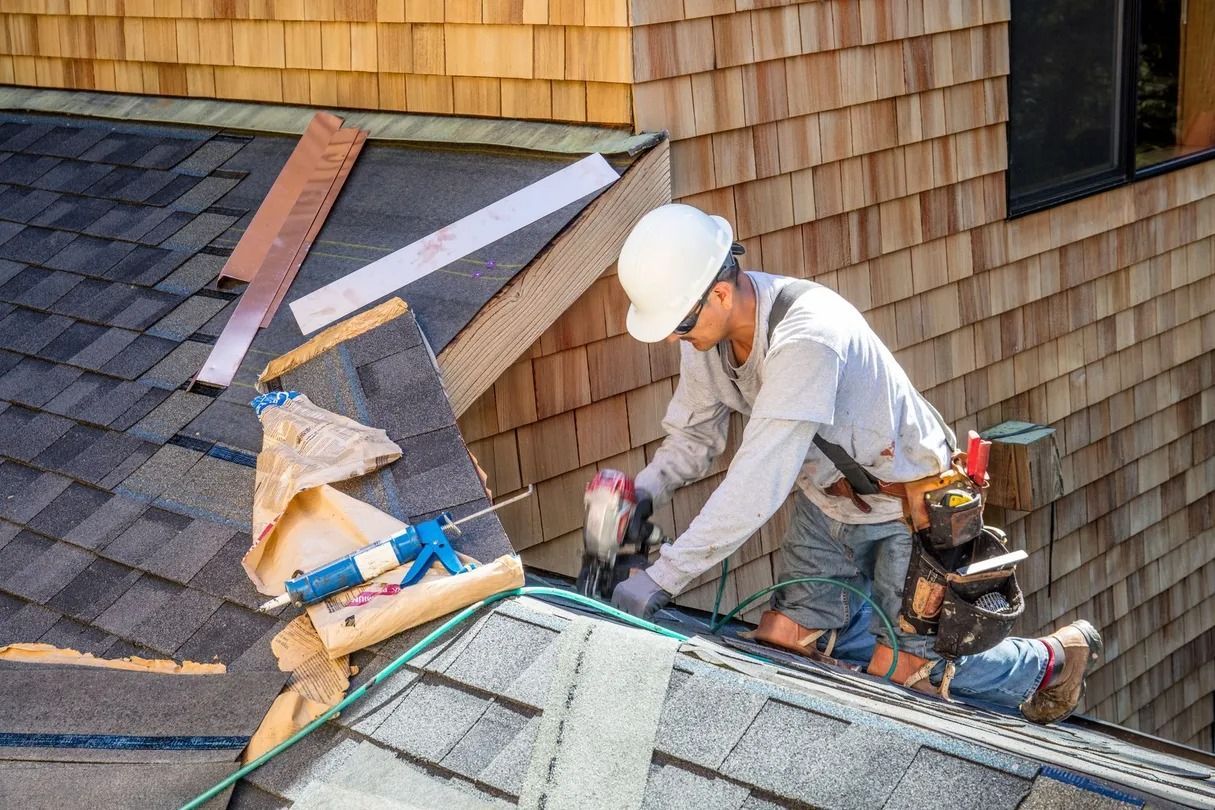 Roofing worker repairing shingles on a house roof with tools and materials nearby