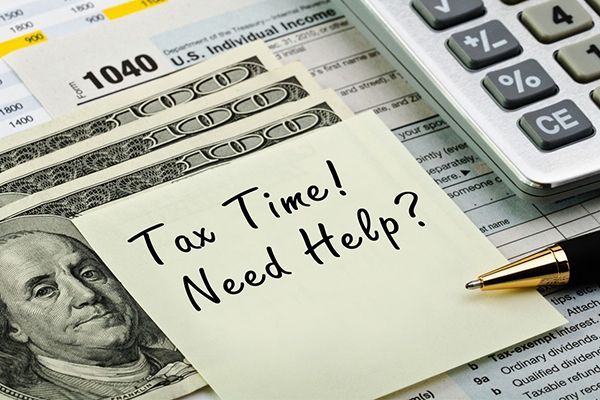 A 1040 tax form with a sticky note that says tax time need help