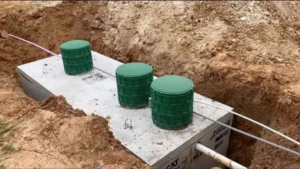 Concrete utility box with three green caps in a dirt trench