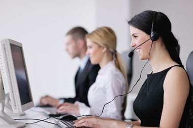 A woman wearing a headset is sitting in front of a computer.