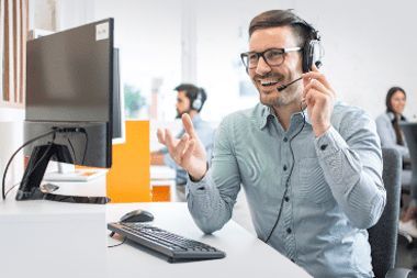 A man wearing a headset is sitting at a desk in front of a computer.