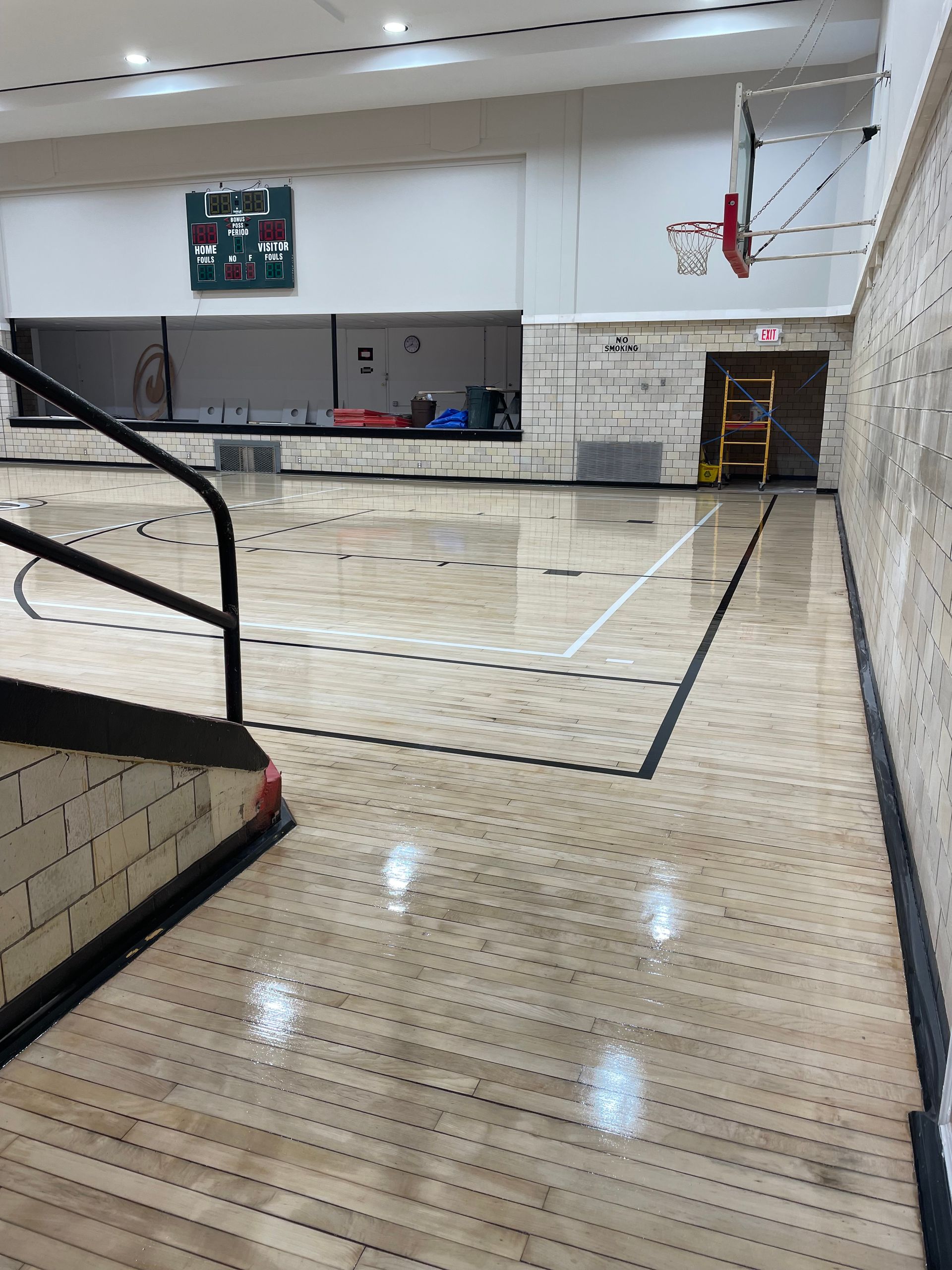 A basketball court in a gym with stairs leading up to it.