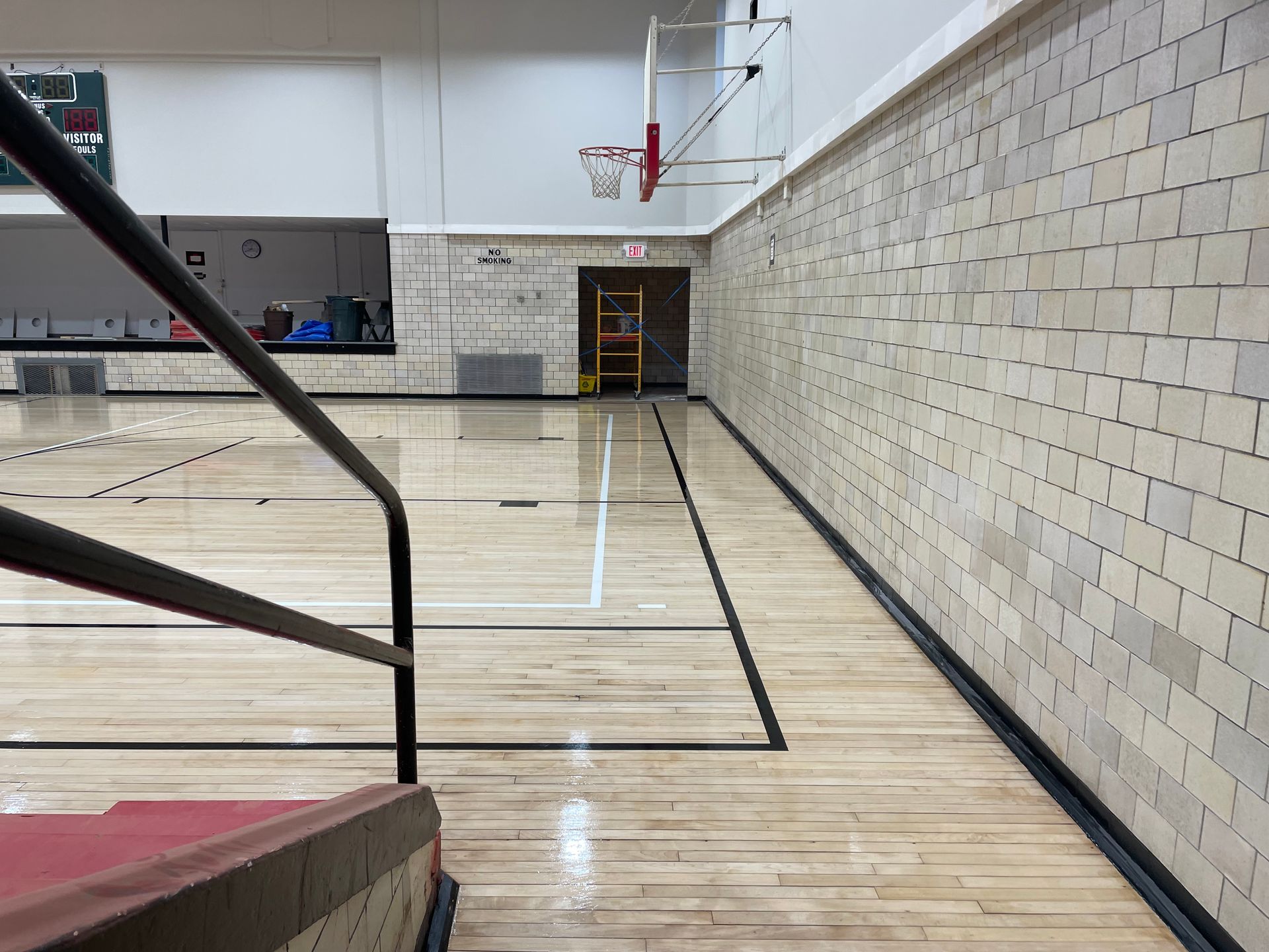 A basketball court with a wooden floor and a brick wall.