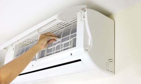 A person is cleaning the filter of an air conditioner.
