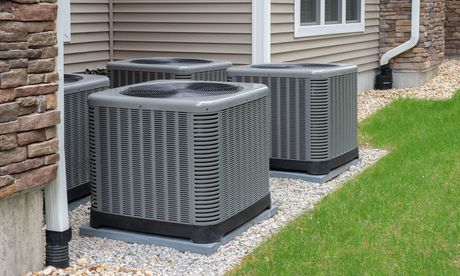 Three air conditioners are sitting outside of a house.