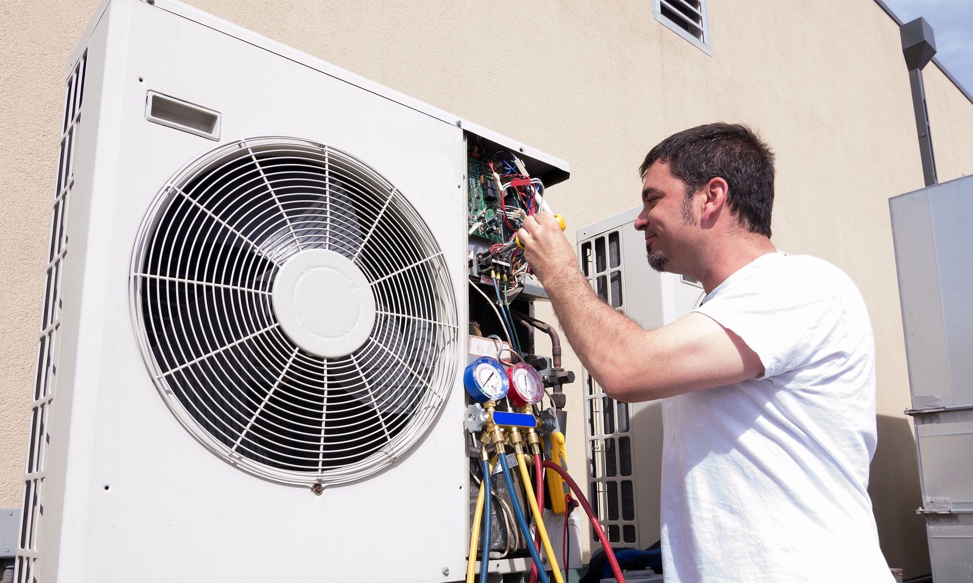 A man is working on an air conditioner outside of a building