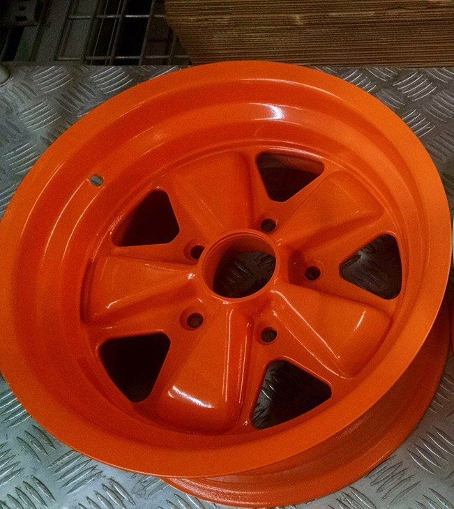 An orange wheel is sitting on a metal surface