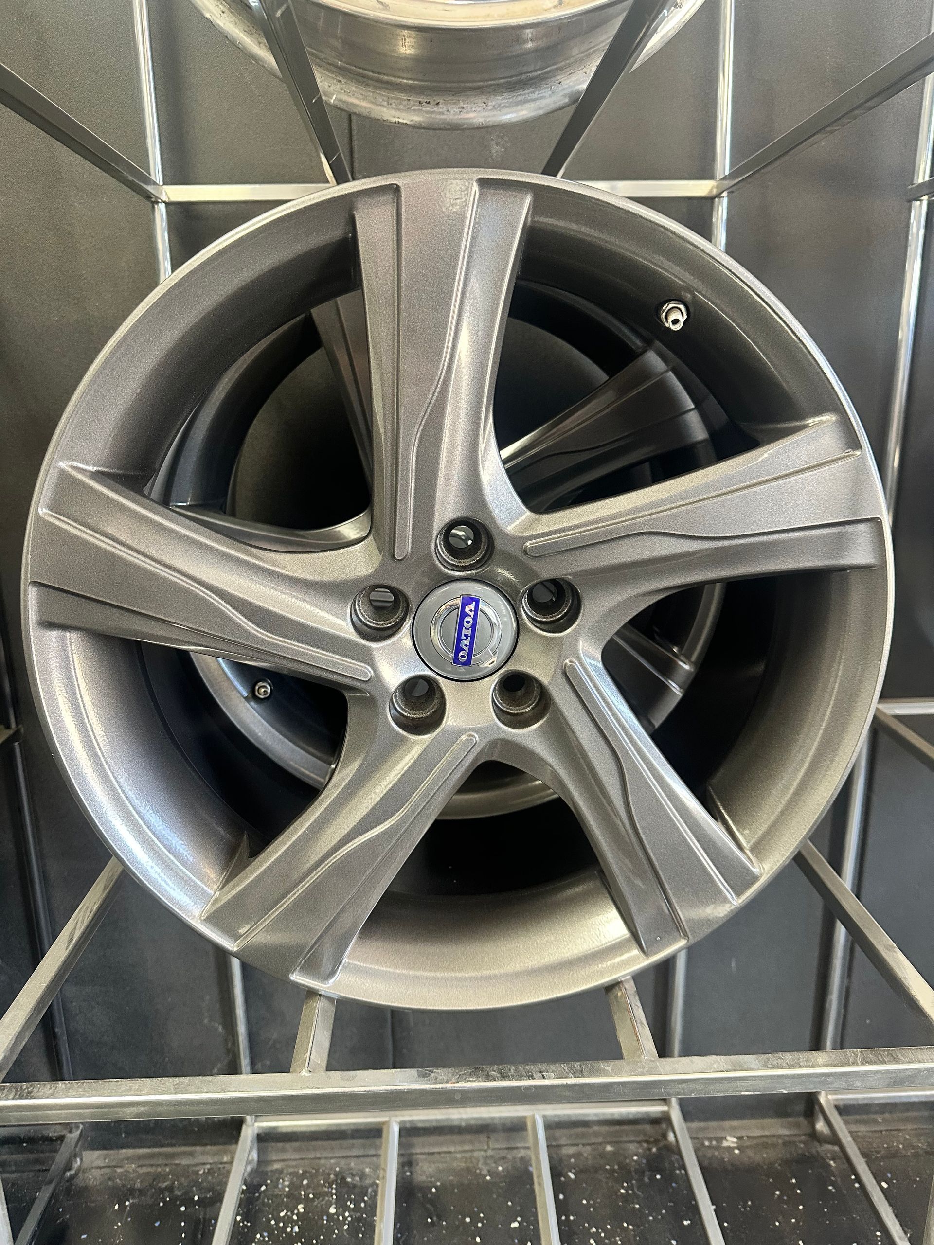Gray alloy wheel with five spokes, featuring a Volvo logo at its center.