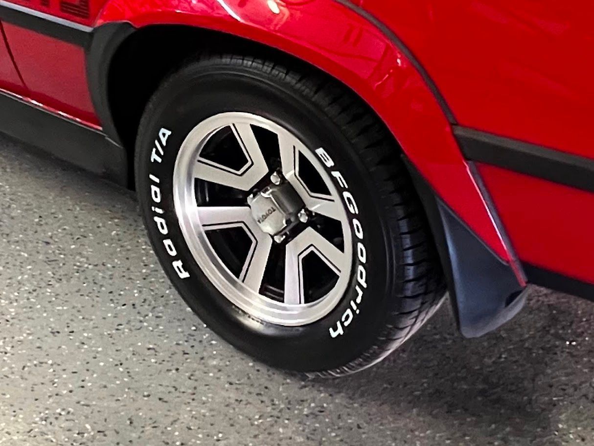 Close-up of a red classic car's rear wheel with a silver and black rim and a BFGoodrich Radial T/A tire.