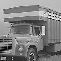 A black and white photo of a truck parked in a field.