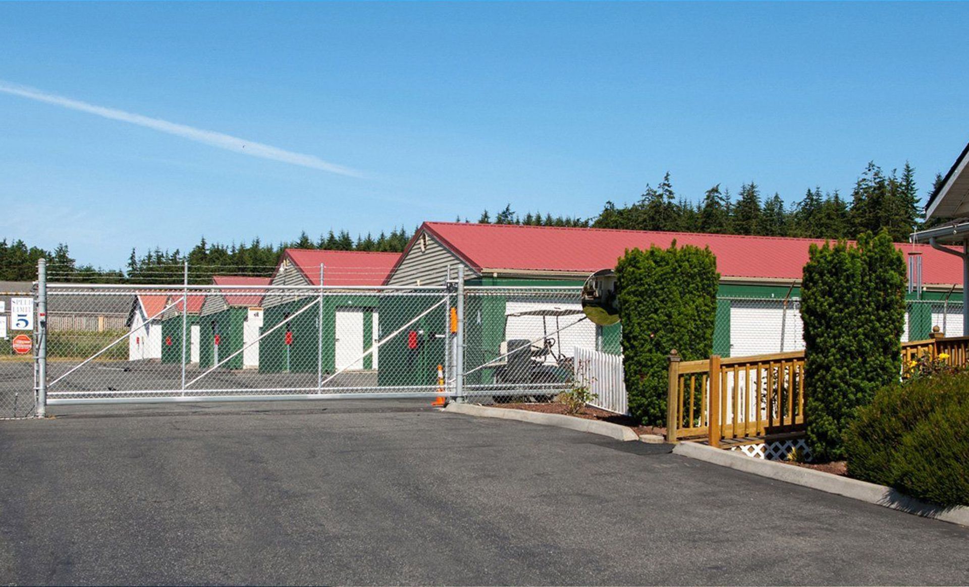 a gated entrance to a storage facility with a red roof