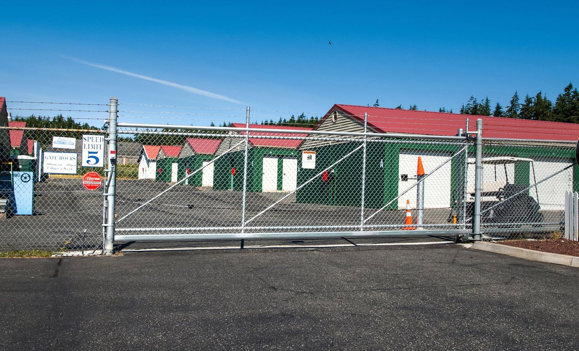 a chain link fence surrounds a parking lot with a building in the background .