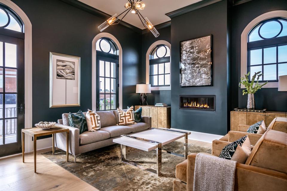 Living room with dark gray walls, large windows, a sofa, armchairs, and a fireplace.