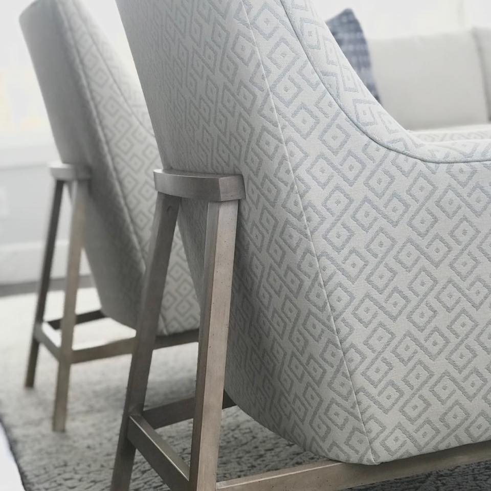 Two upholstered chairs with geometric patterned fabric, set on a rug in a bright room.