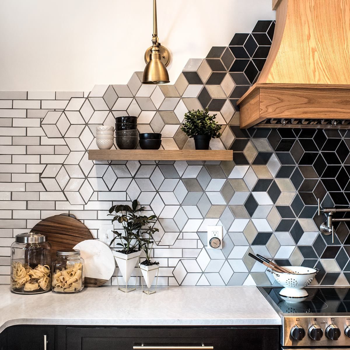 Kitchen with cube-patterned tiles in various shades, a wooden shelf, and a wooden range hood above the stove.