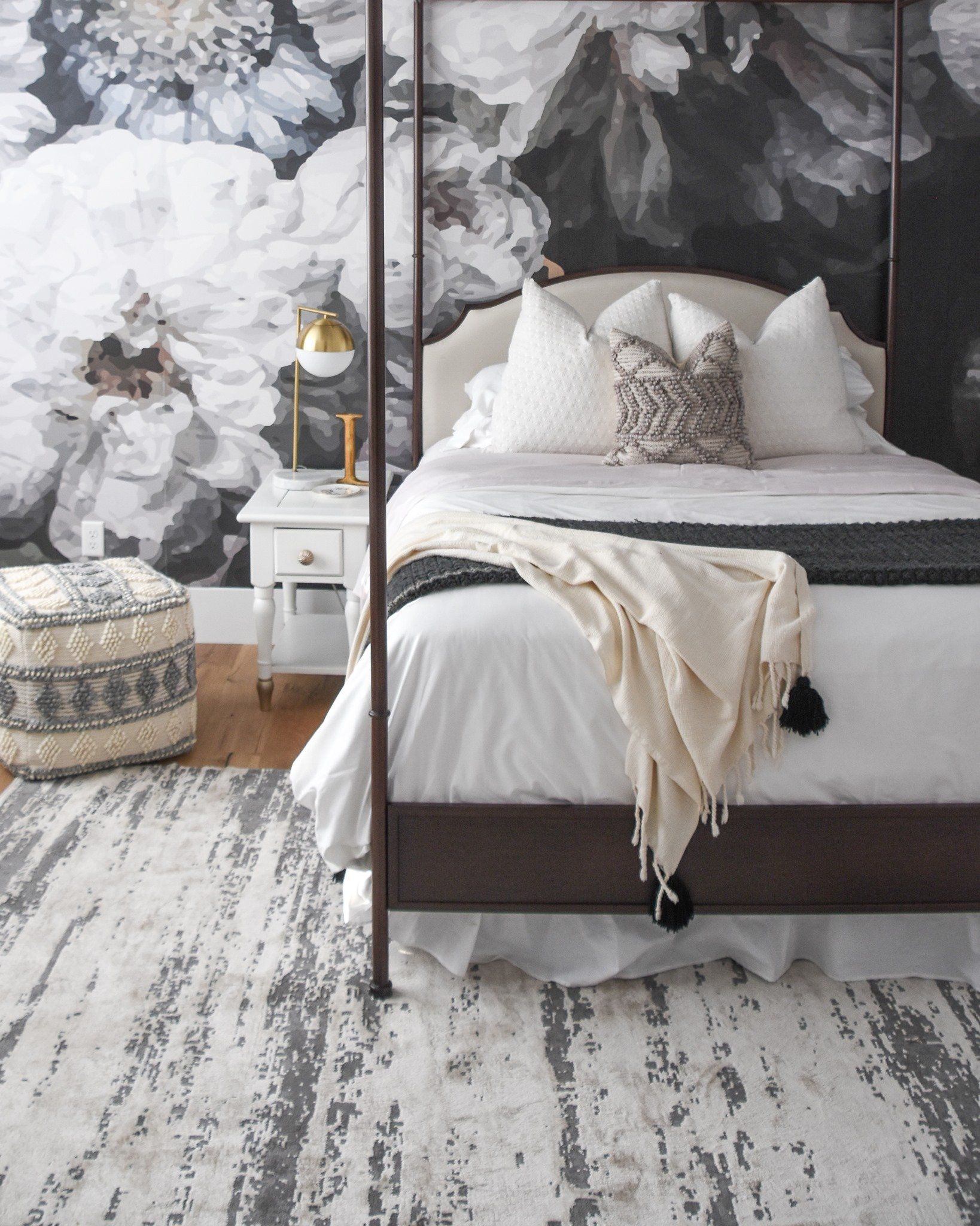 Bedroom with floral wallpaper, a four-poster bed, white bedding, decorative pillows, and a patterned rug.