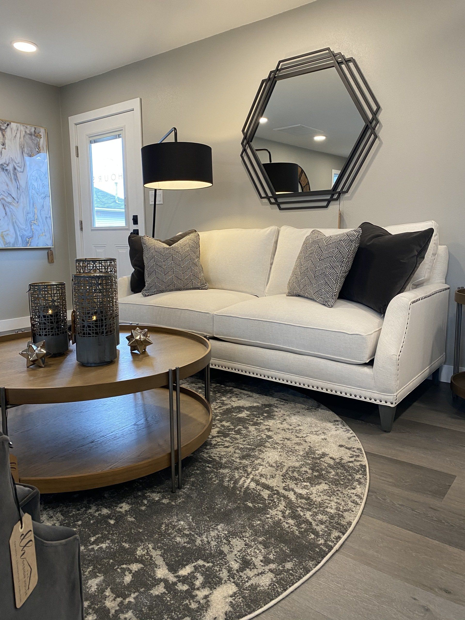Living room with white sofa, round coffee table, circular rug, and geometric mirror.