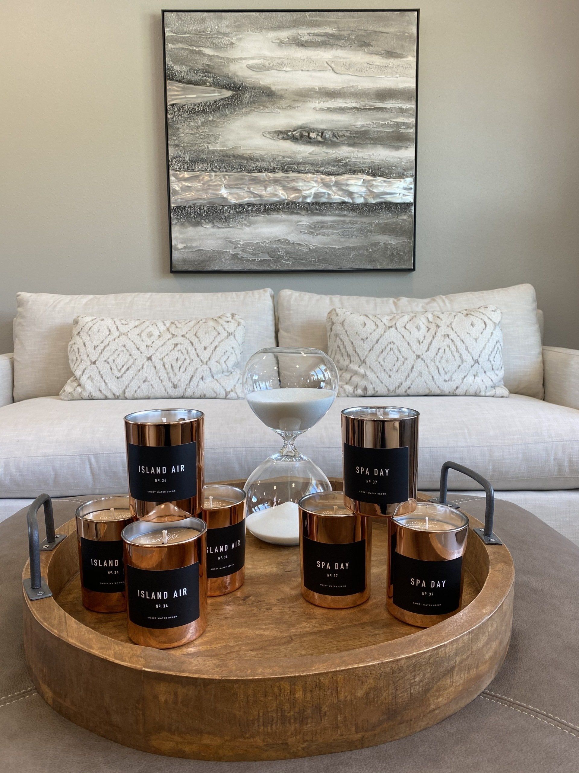 A coffee table with candles, an hourglass, and decorative pillows in a living room setting.