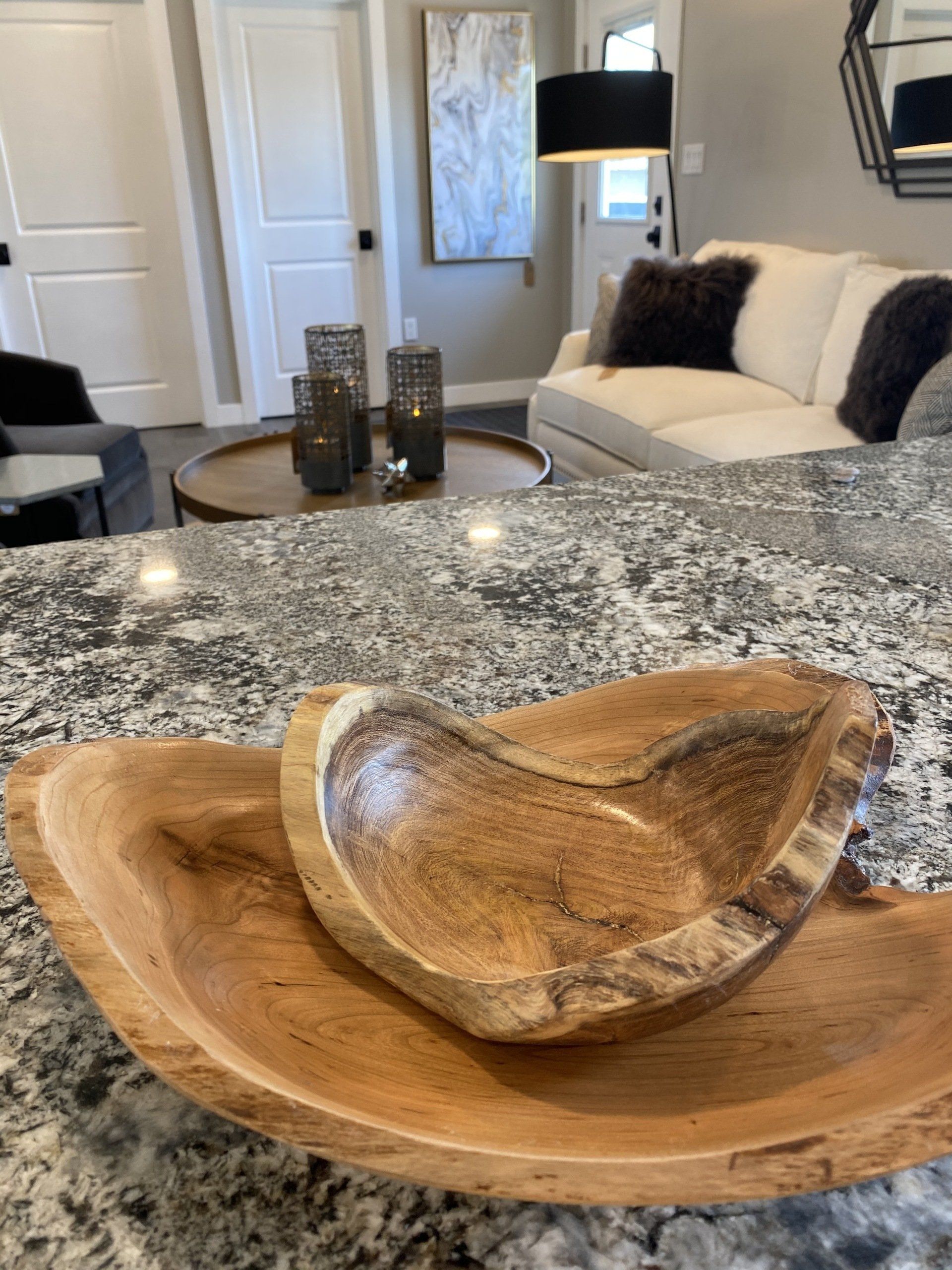 Wooden bowls on a granite countertop, with a living room in the background.
