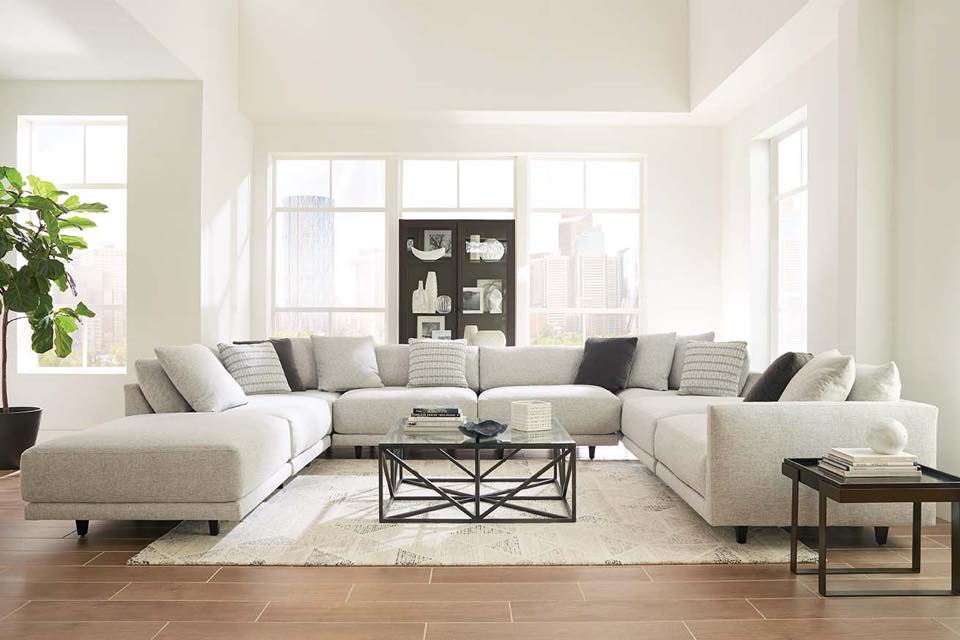 U-shaped light gray sectional sofa in a bright living room with a modern coffee table and side table.