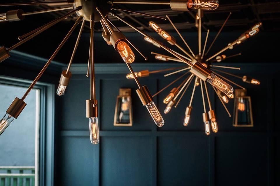 Ornate brass light fixtures against a dark blue wall with sconces.