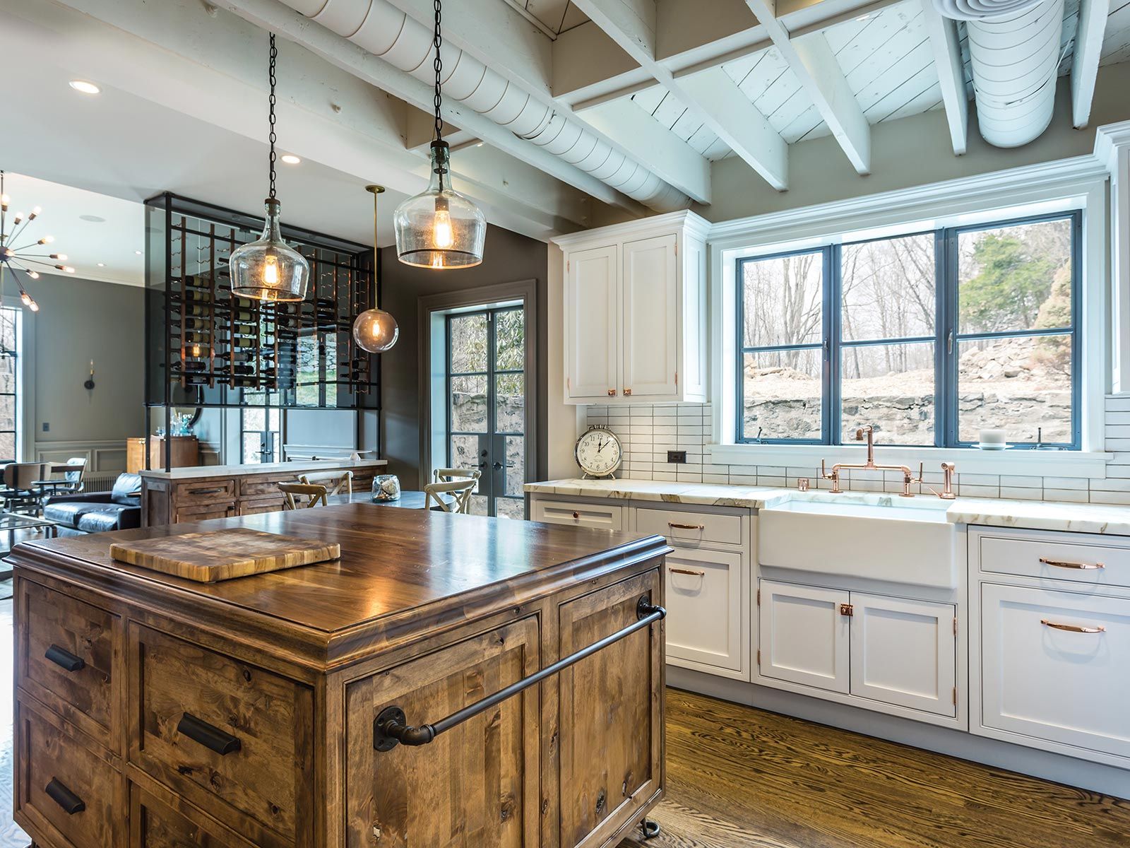 Kitchen with wooden island, white cabinets, copper fixtures, and glass pendant lights.