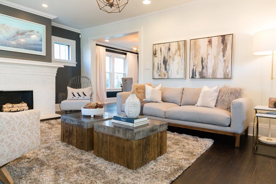 Cozy living room with gray sofa, wooden coffee tables, and abstract art.