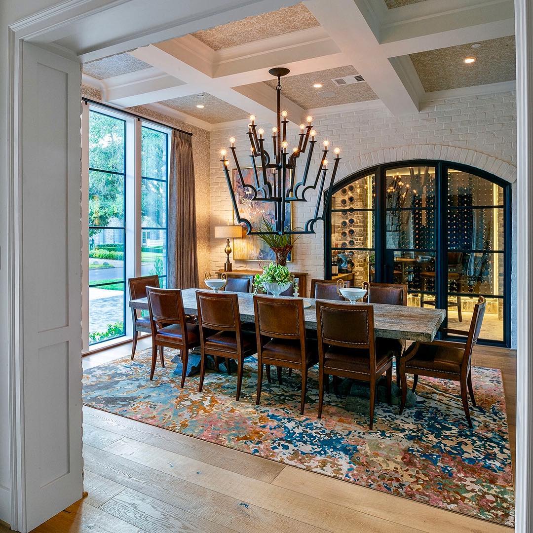 Elegant dining room with a long table, chandelier, and wine cellar.