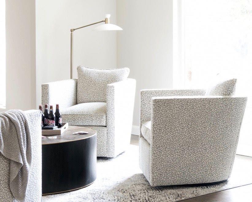 Two patterned armchairs, round coffee table, and floor lamp in a bright living room.