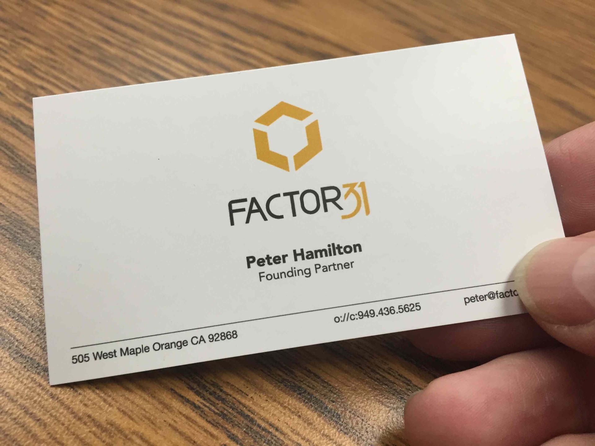 A person is holding a business card for peter hamilton