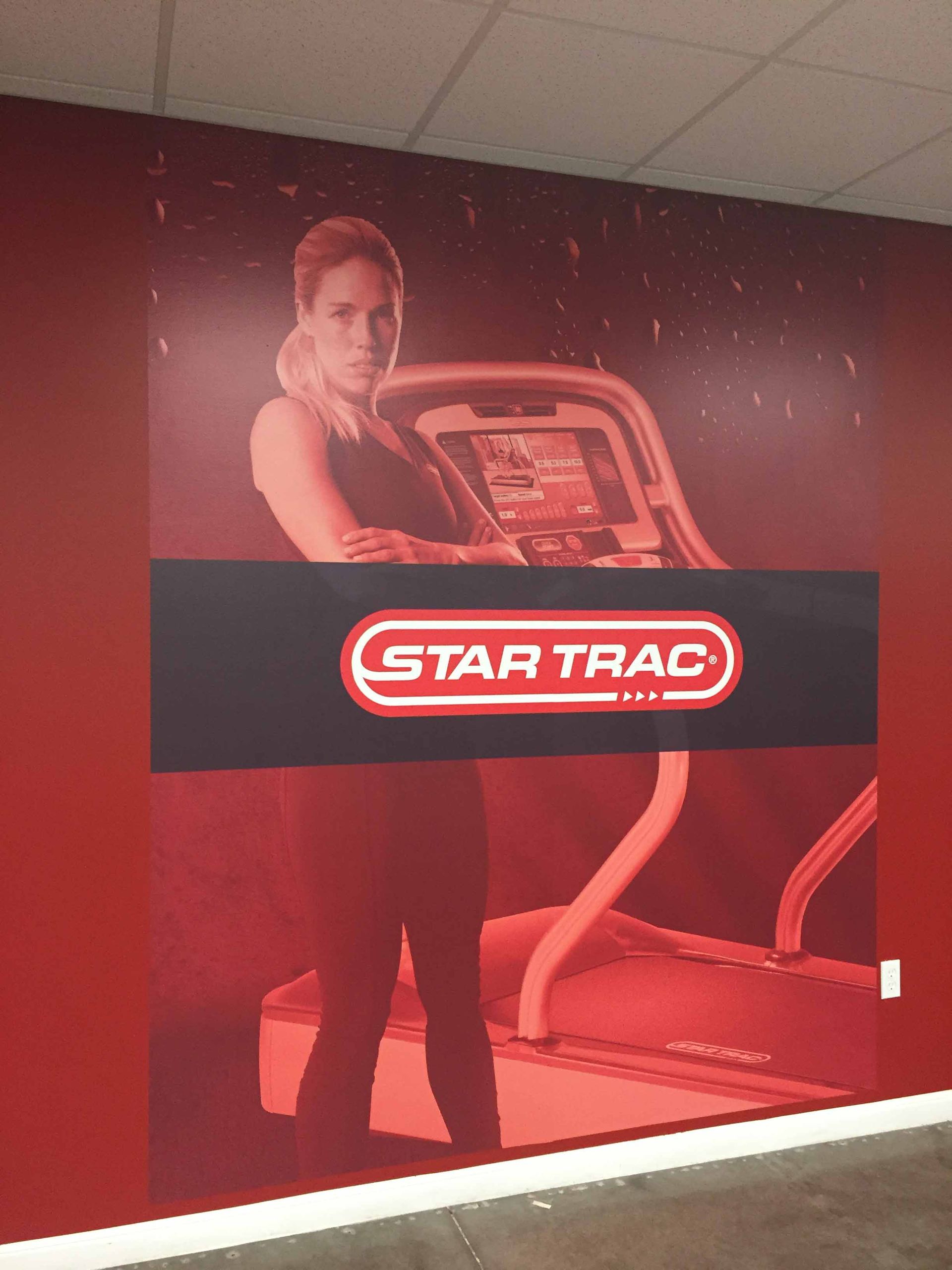 A poster of a woman on a treadmill with the star trac logo