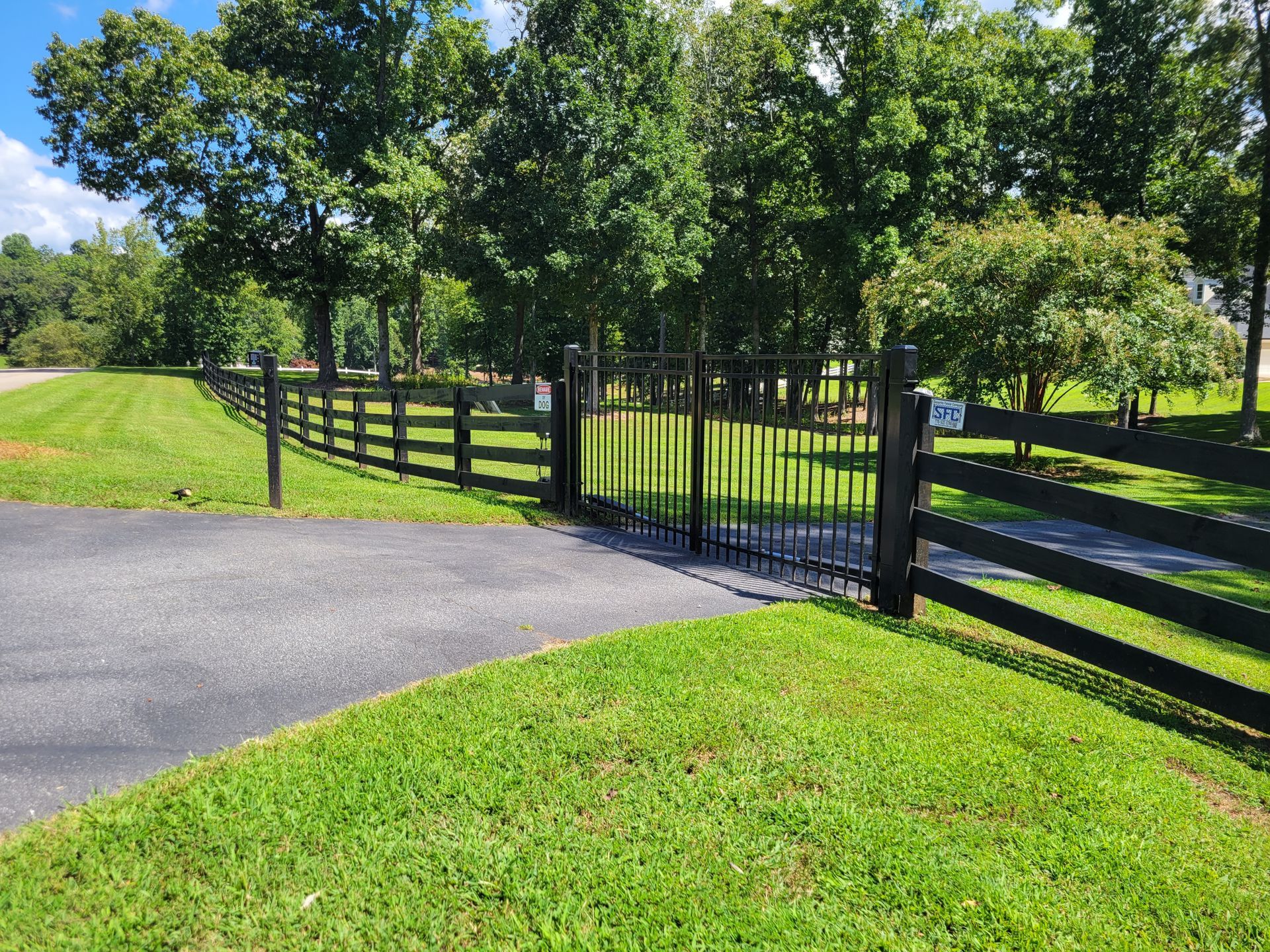 A black fence surrounds a lush green field.
