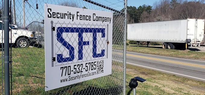 A security fence company sign is hanging on a chain link fence.