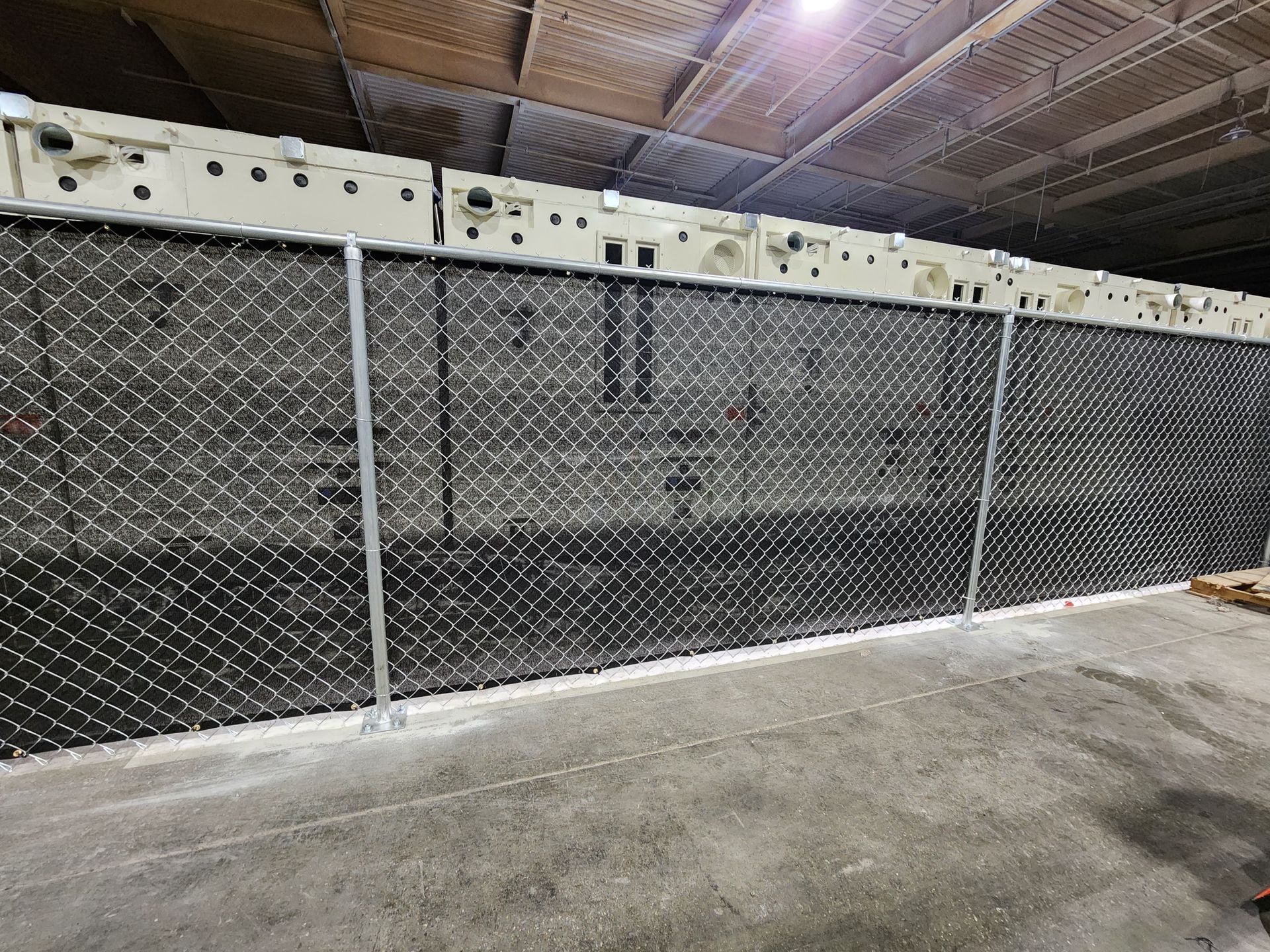 There is a chain link fence in the middle of a warehouse.
