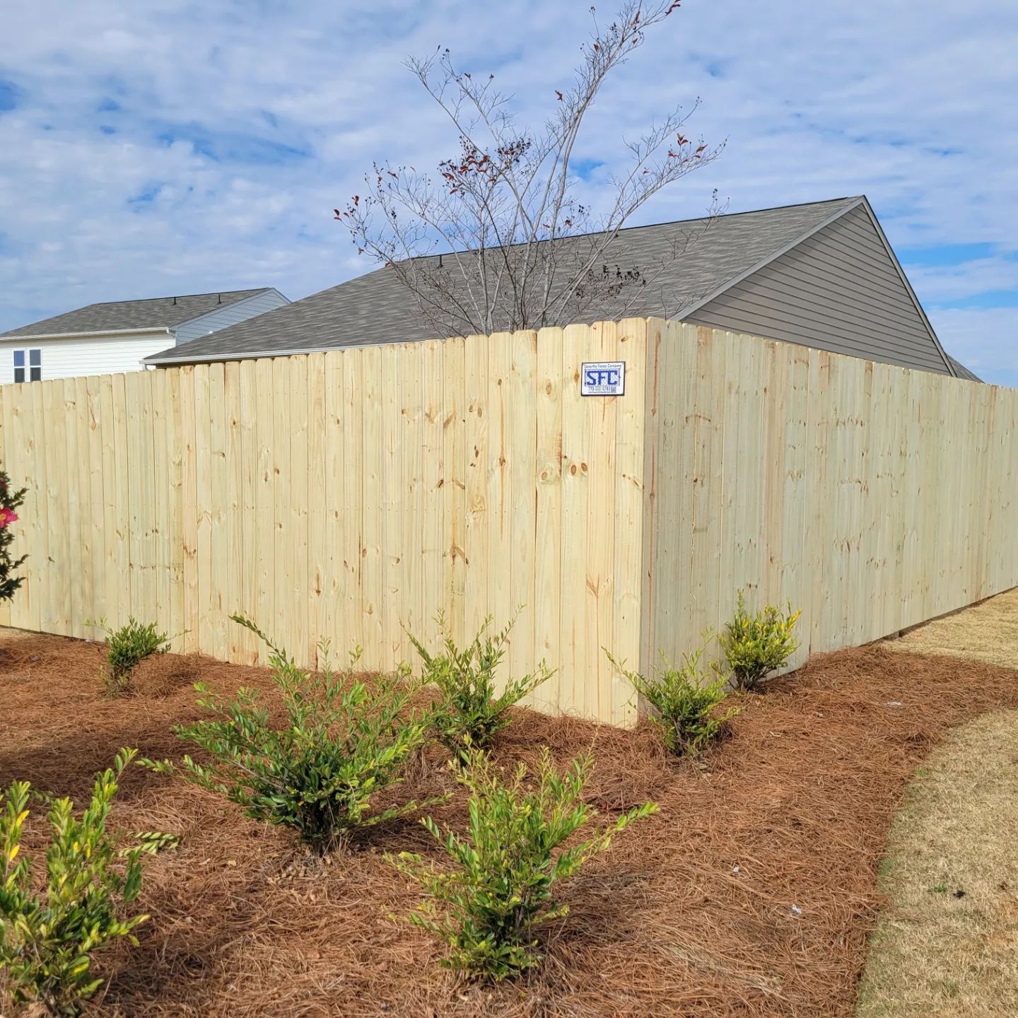 A wooden fence is in front of a house.