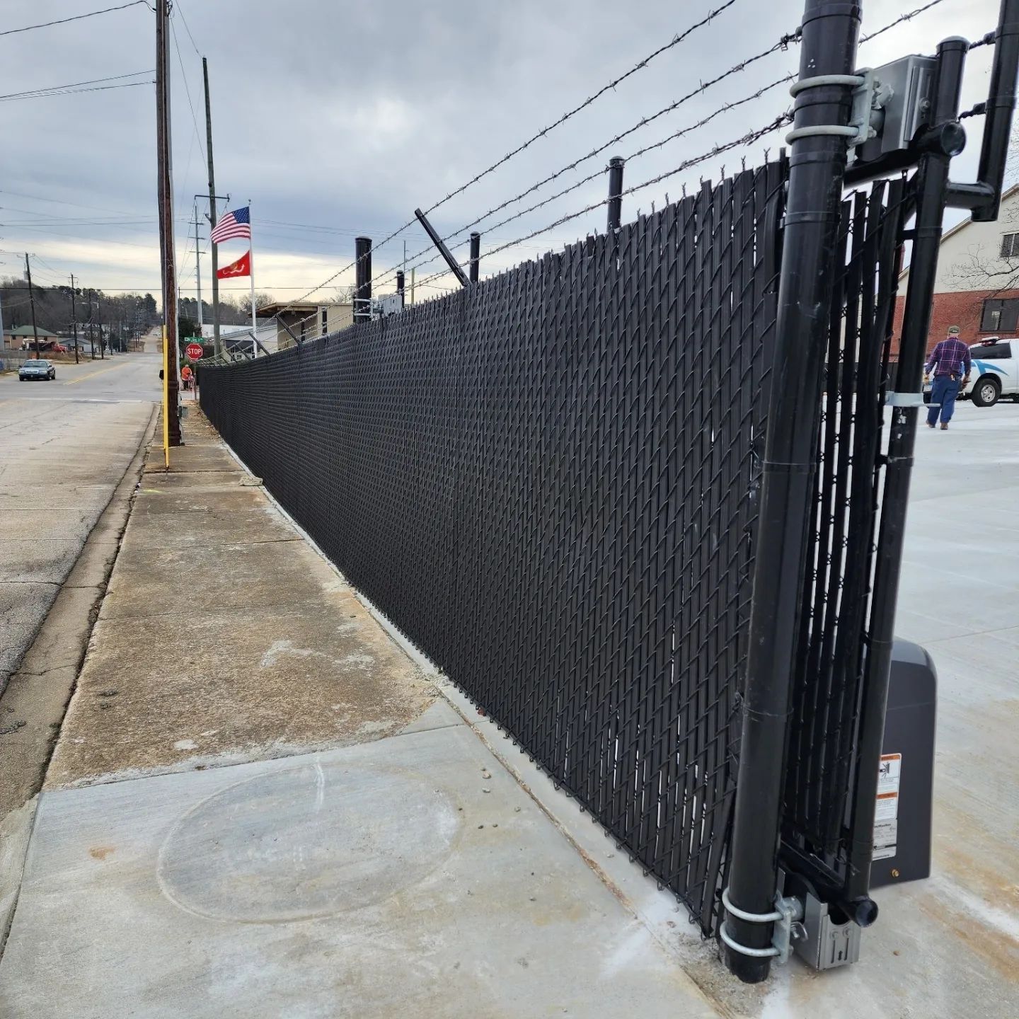 A black chain link fence with barbed wire along the side of the road