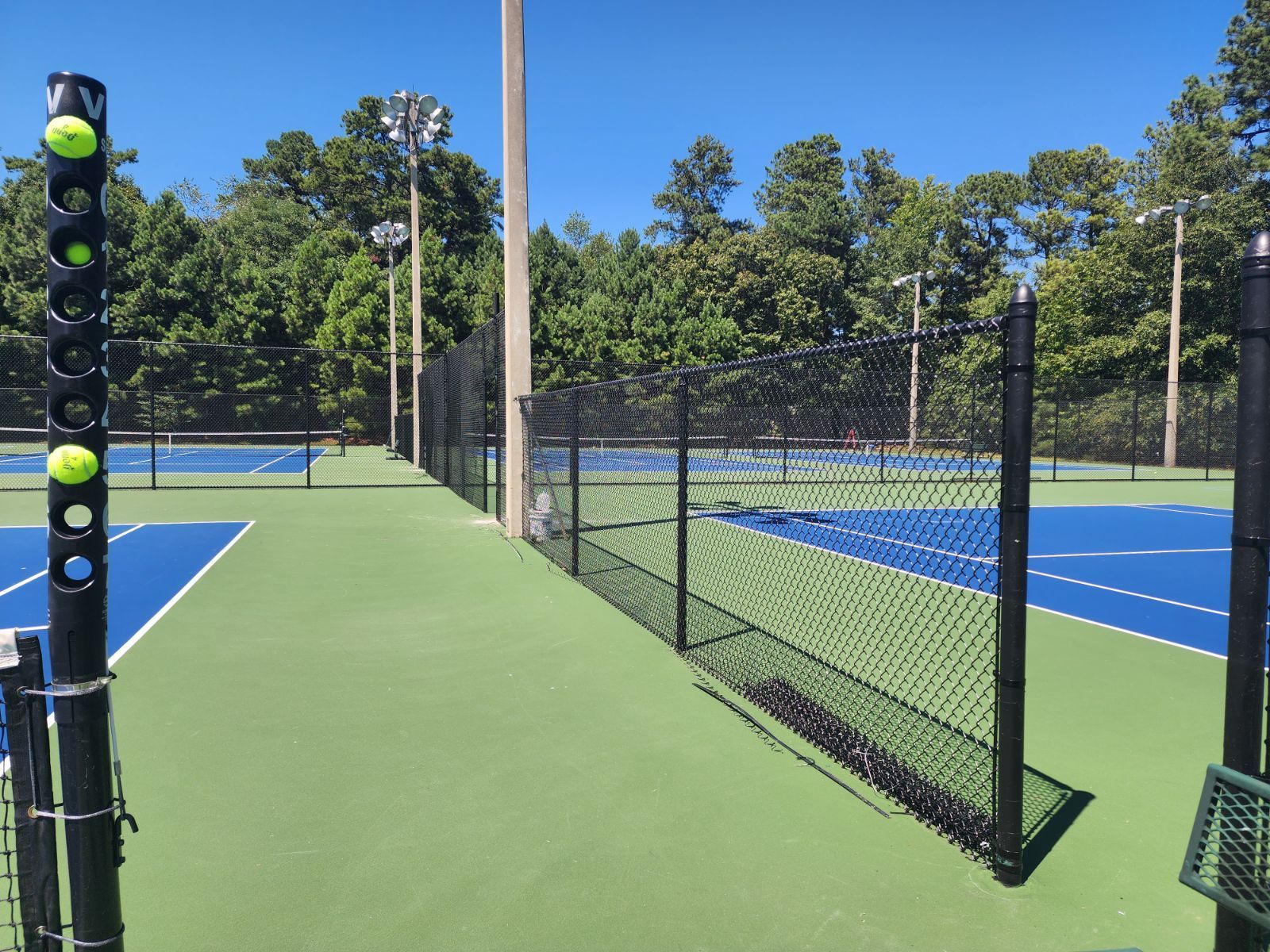 A tennis court with a fence and a bunch of tennis balls