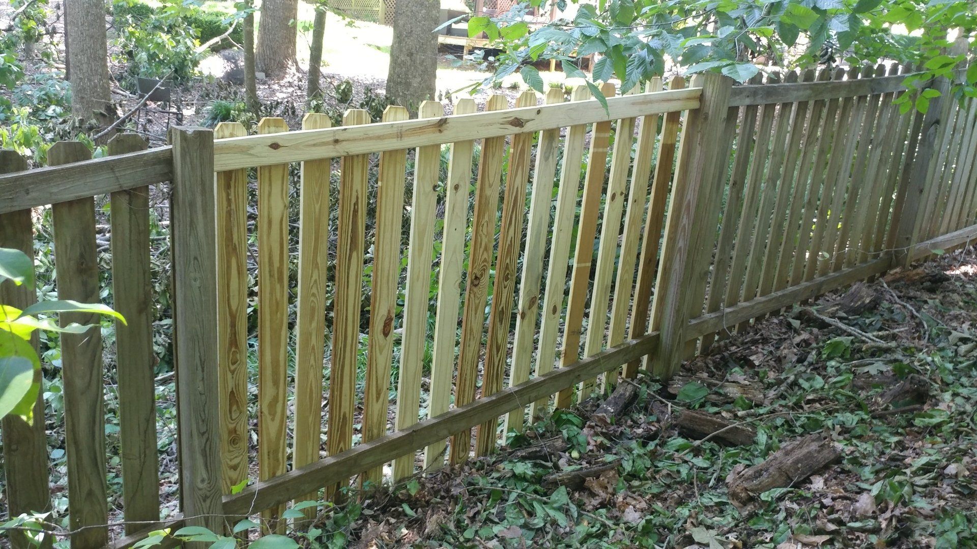 A wooden fence is surrounded by trees and leaves