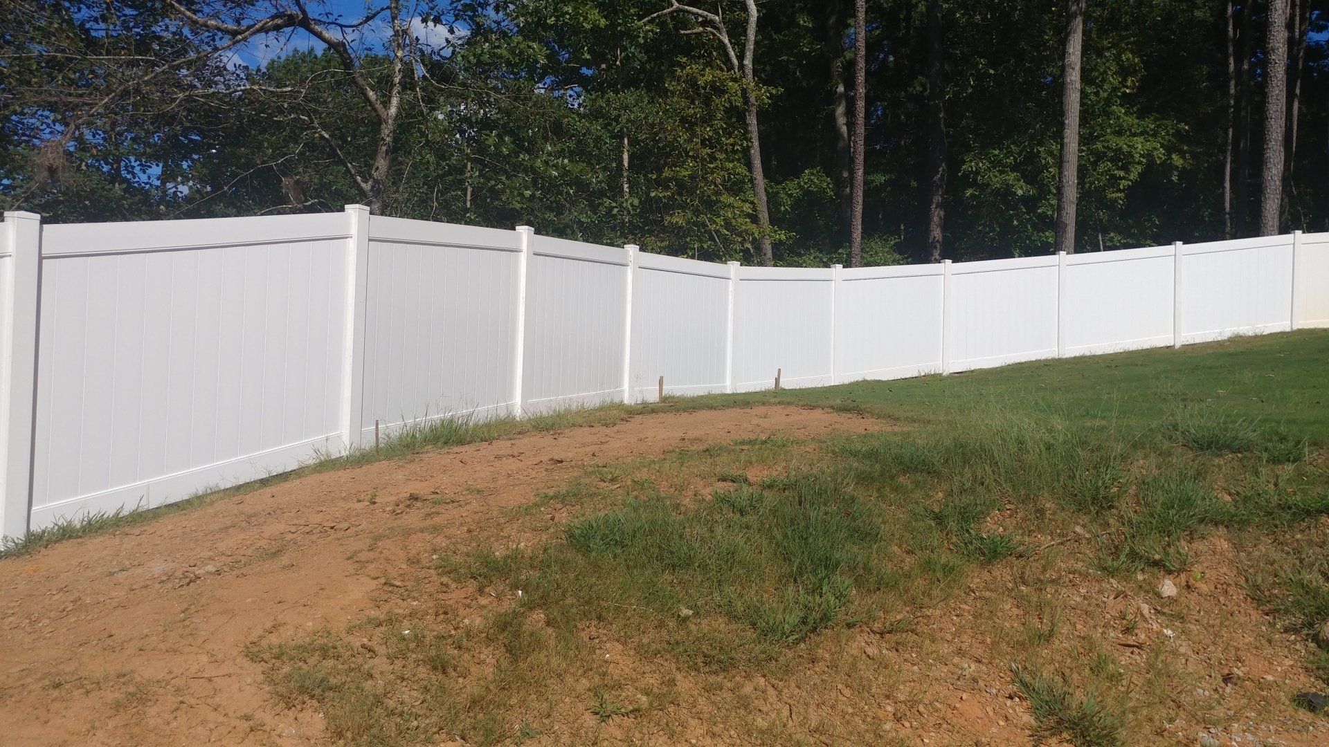 A white fence is surrounding a lush green field.