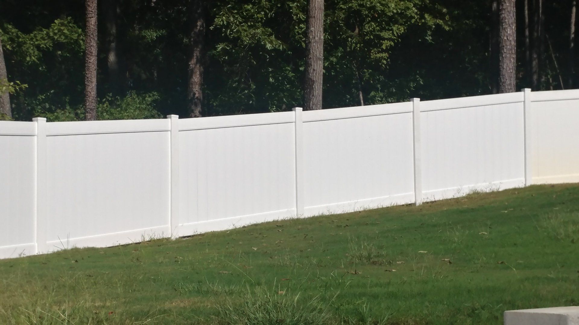 A white fence is surrounding a lush green field.