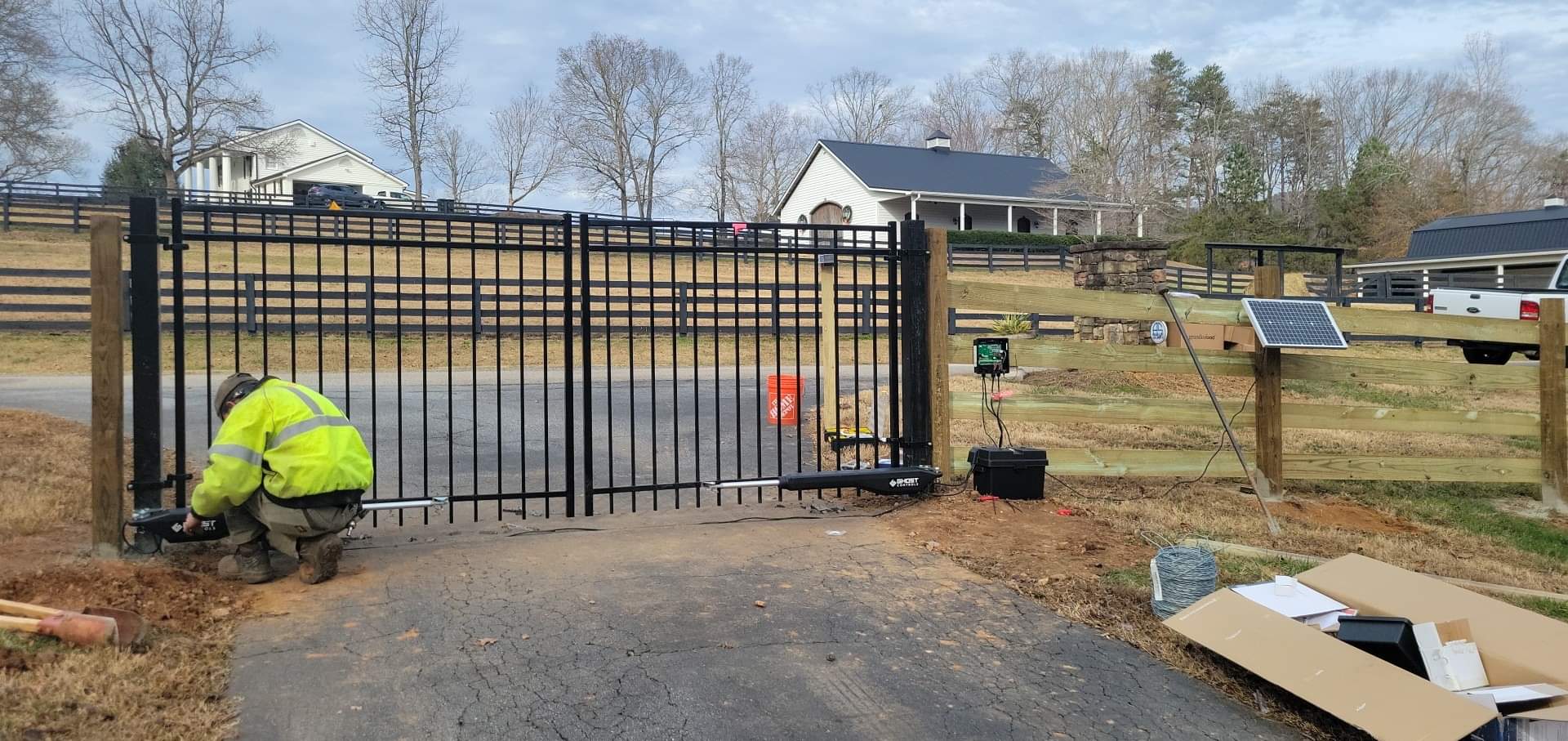 A man is working on a gate in a driveway.